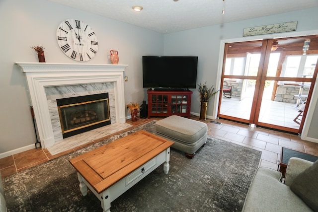 living area featuring baseboards, french doors, tile patterned floors, and a high end fireplace