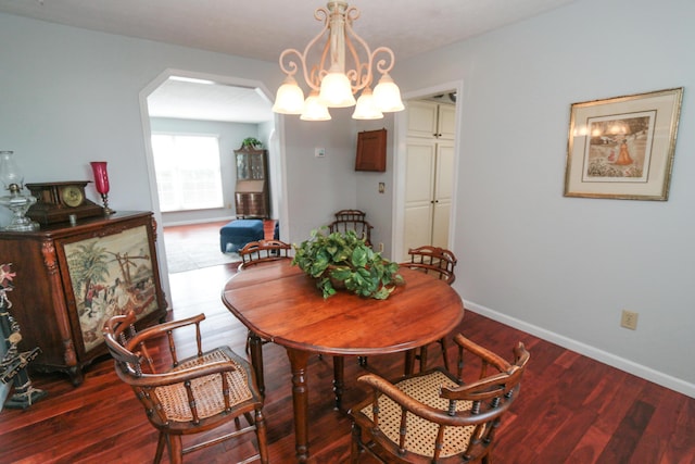 dining room featuring arched walkways, baseboards, an inviting chandelier, and wood finished floors