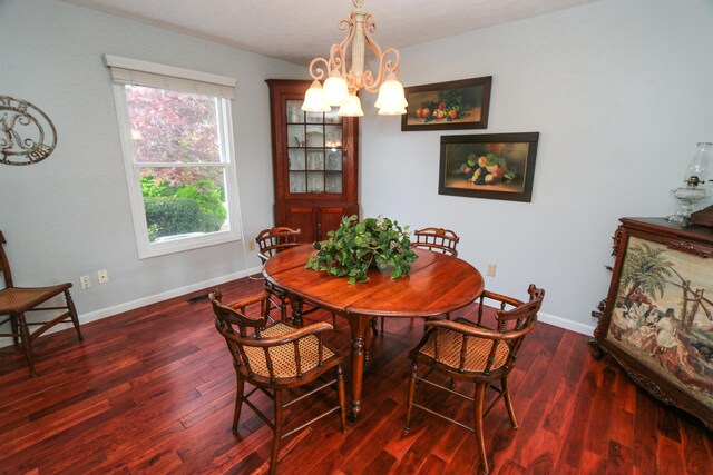 dining room featuring a chandelier, baseboards, visible vents, and wood finished floors
