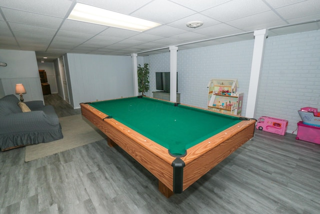 rec room with a drop ceiling, billiards, brick wall, and wood finished floors