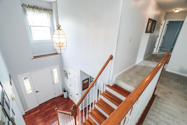 entryway with an inviting chandelier, plenty of natural light, baseboards, and a high ceiling