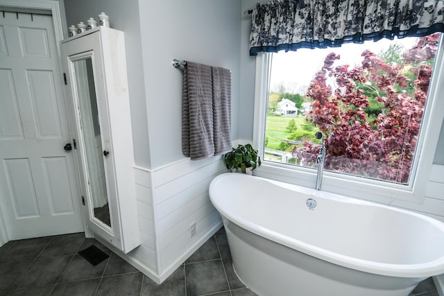 full bath featuring tile patterned flooring, a freestanding bath, and a wainscoted wall
