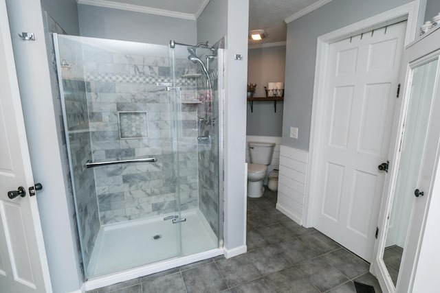 bathroom featuring toilet, tile patterned flooring, a stall shower, and ornamental molding