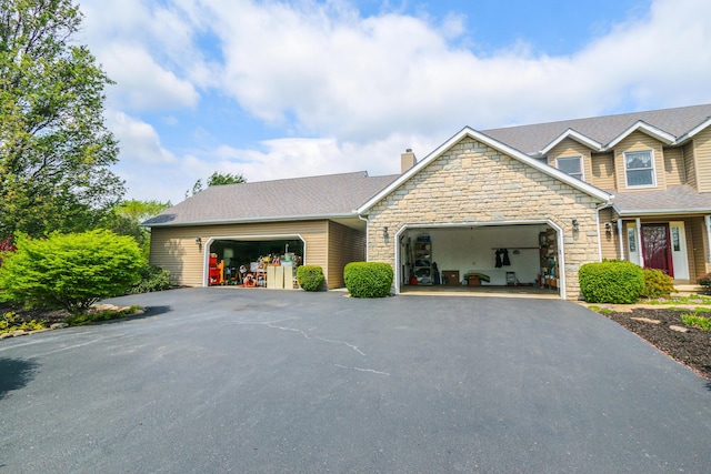 view of front of home featuring a chimney, stone siding, aphalt driveway, and a garage