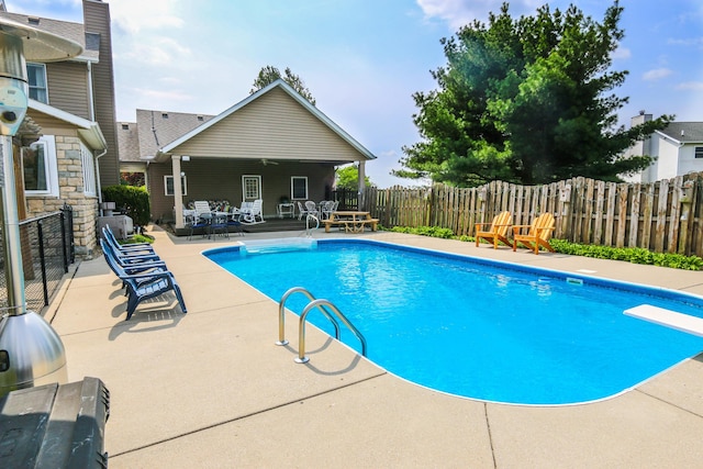 view of swimming pool with a patio area, a fenced in pool, a fenced backyard, and a diving board