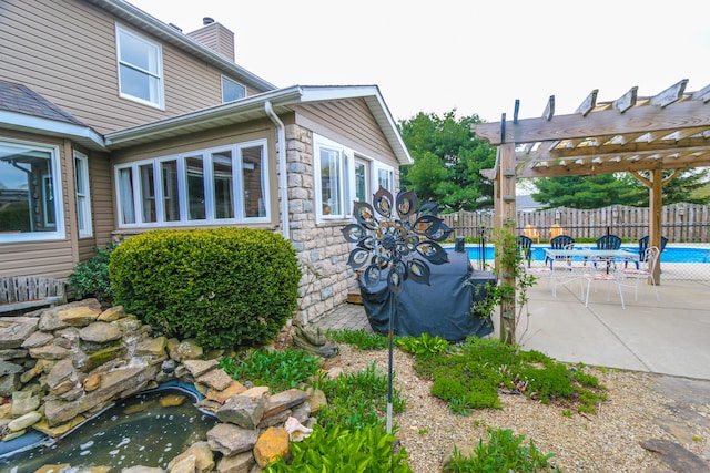 view of home's exterior with a pergola, fence, a fenced in pool, and stone siding