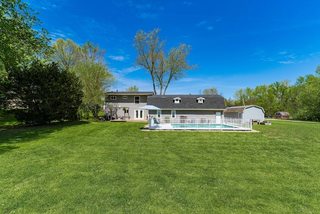 rear view of house featuring a yard, an outdoor pool, an outdoor structure, and a storage unit