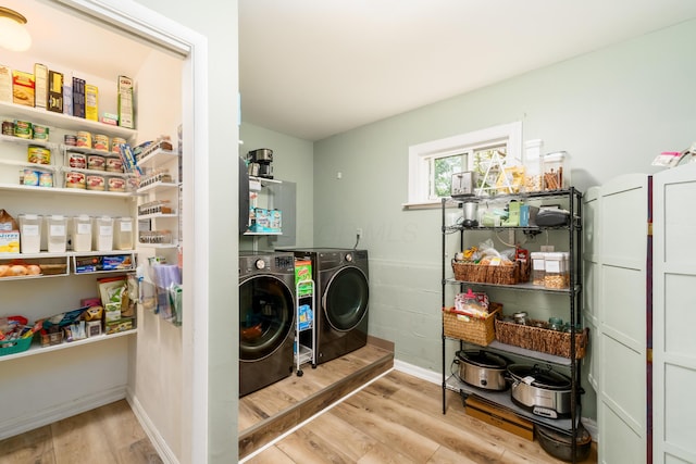 clothes washing area with laundry area, baseboards, independent washer and dryer, and wood finished floors