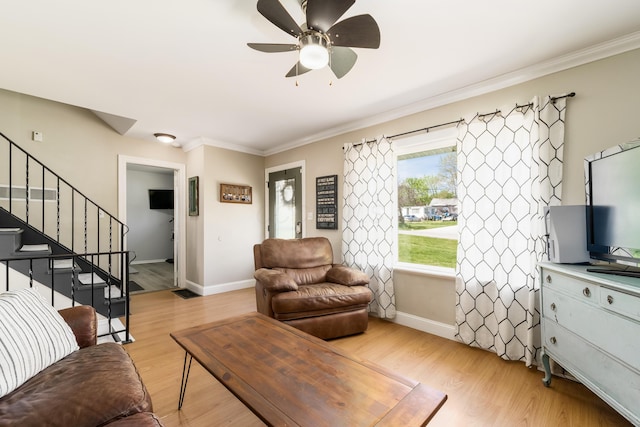 living area featuring baseboards, ornamental molding, light wood finished floors, and stairway