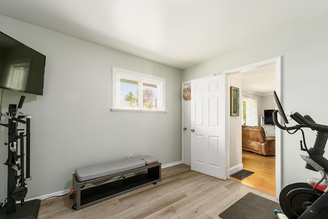 workout area with baseboards and light wood-style flooring