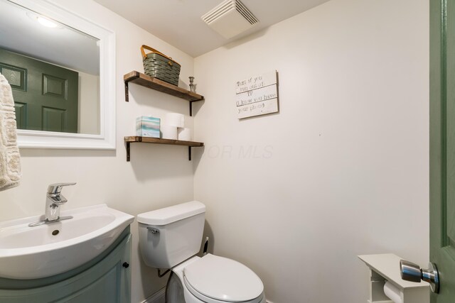 half bathroom featuring toilet, visible vents, and vanity