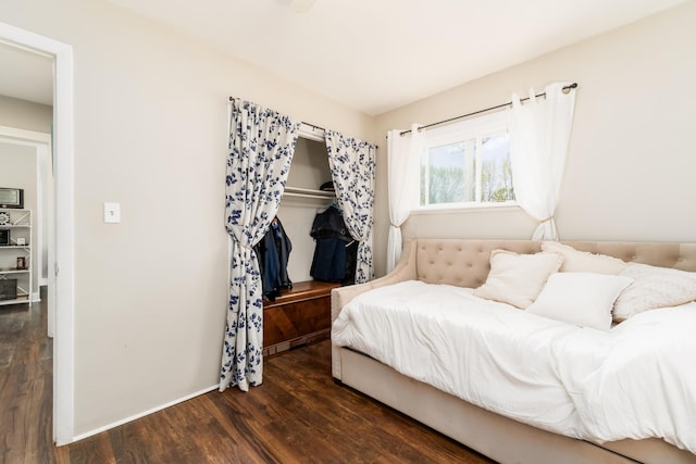 bedroom featuring baseboards, wood finished floors, and a closet