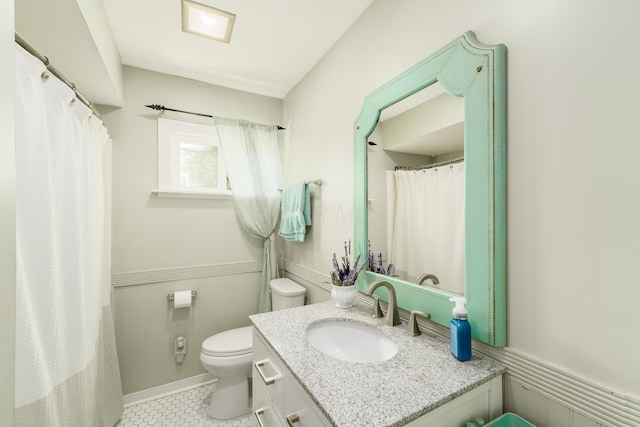 bathroom with vanity, tile patterned floors, toilet, and a wainscoted wall