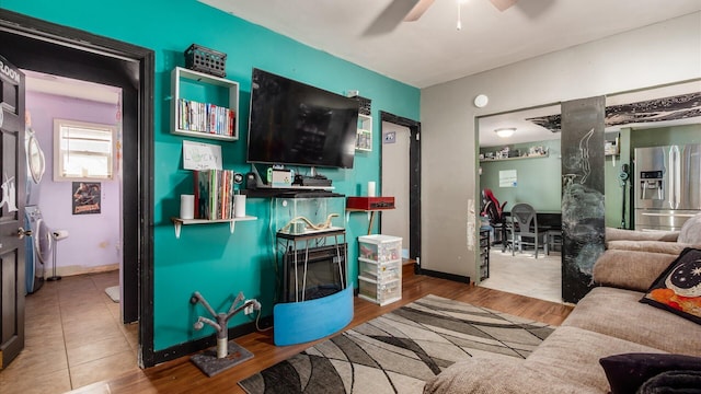 living area featuring baseboards, ceiling fan, washer / clothes dryer, and wood finished floors