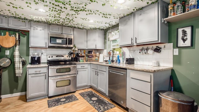 kitchen with a sink, gray cabinets, and appliances with stainless steel finishes