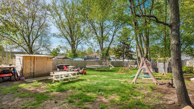 view of yard with a storage shed, an outbuilding, a fenced backyard, and a trampoline