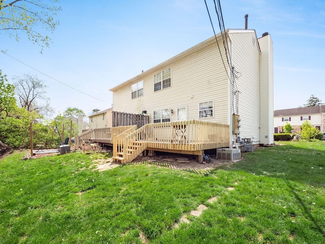 rear view of property with a chimney, a yard, central AC, and a deck
