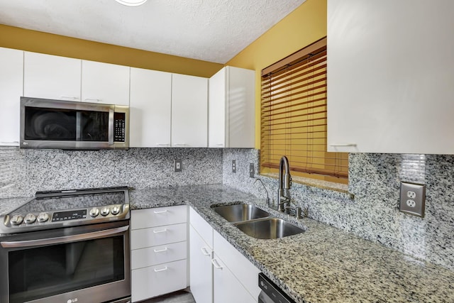 kitchen featuring decorative backsplash, white cabinetry, light stone counters, a sink, and appliances with stainless steel finishes