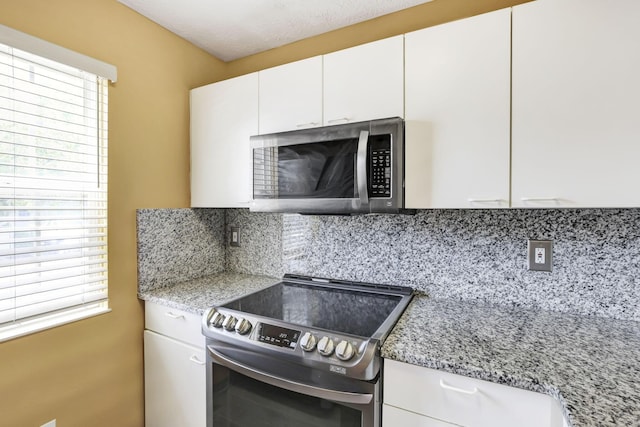 kitchen featuring backsplash, stainless steel appliances, white cabinetry, and a wealth of natural light