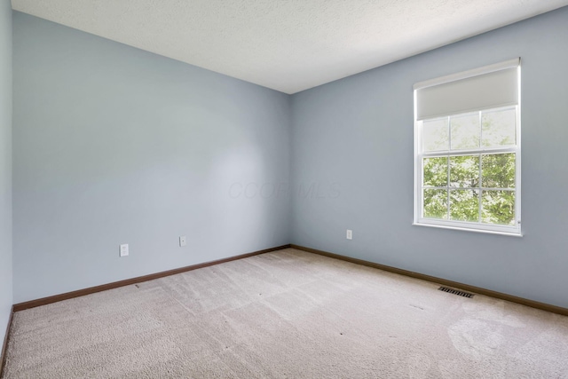 spare room with baseboards, carpet flooring, a textured ceiling, and visible vents