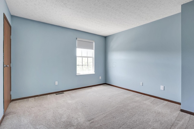 carpeted spare room featuring a textured ceiling, baseboards, and visible vents