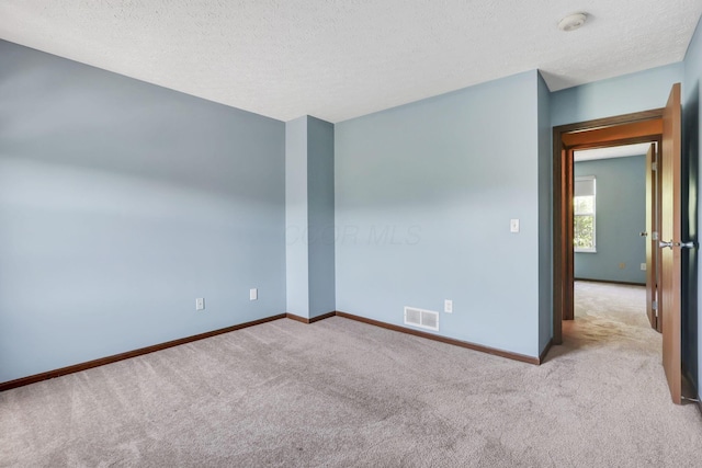 empty room featuring baseboards, carpet, a textured ceiling, and visible vents