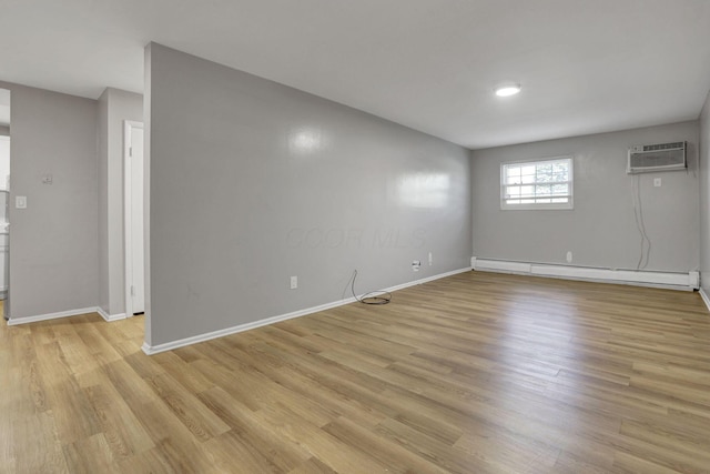interior space featuring baseboards, a baseboard radiator, light wood-type flooring, and a wall mounted air conditioner