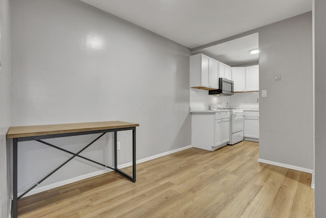 kitchen with light countertops, baseboards, gas range gas stove, and light wood-style flooring