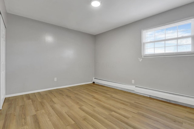 spare room featuring baseboards and light wood finished floors