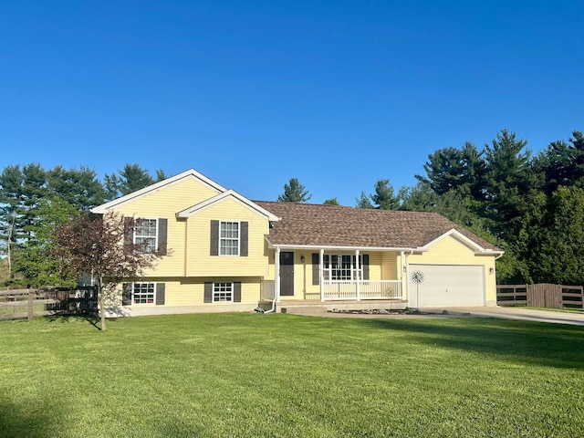 split level home featuring covered porch, an attached garage, fence, and a front lawn