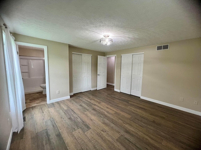 357 Carroll Eastern Rd NW, Baltimore, OH 43105 - unfurnished bedroom featuring baseboards, dark wood-style flooring, visible vents, and two closets