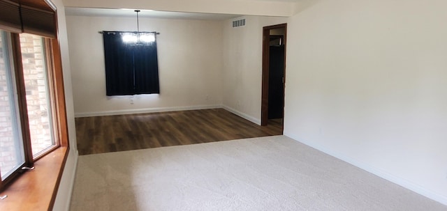unfurnished room featuring plenty of natural light, baseboards, wood finished floors, and visible vents