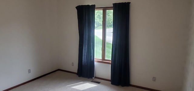 unfurnished room with baseboards, visible vents, and light carpet