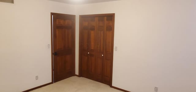 unfurnished bedroom featuring baseboards, visible vents, a closet, and light colored carpet