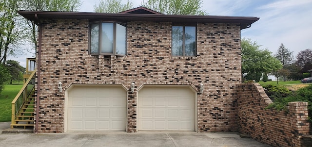 view of front of house featuring an attached garage, stairs, driveway, and brick siding