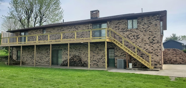 rear view of property featuring central air condition unit, a lawn, a deck, and brick siding