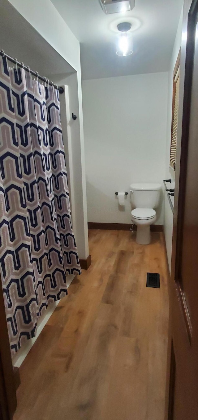 full bathroom with visible vents, wood finished floors, toilet, and curtained shower