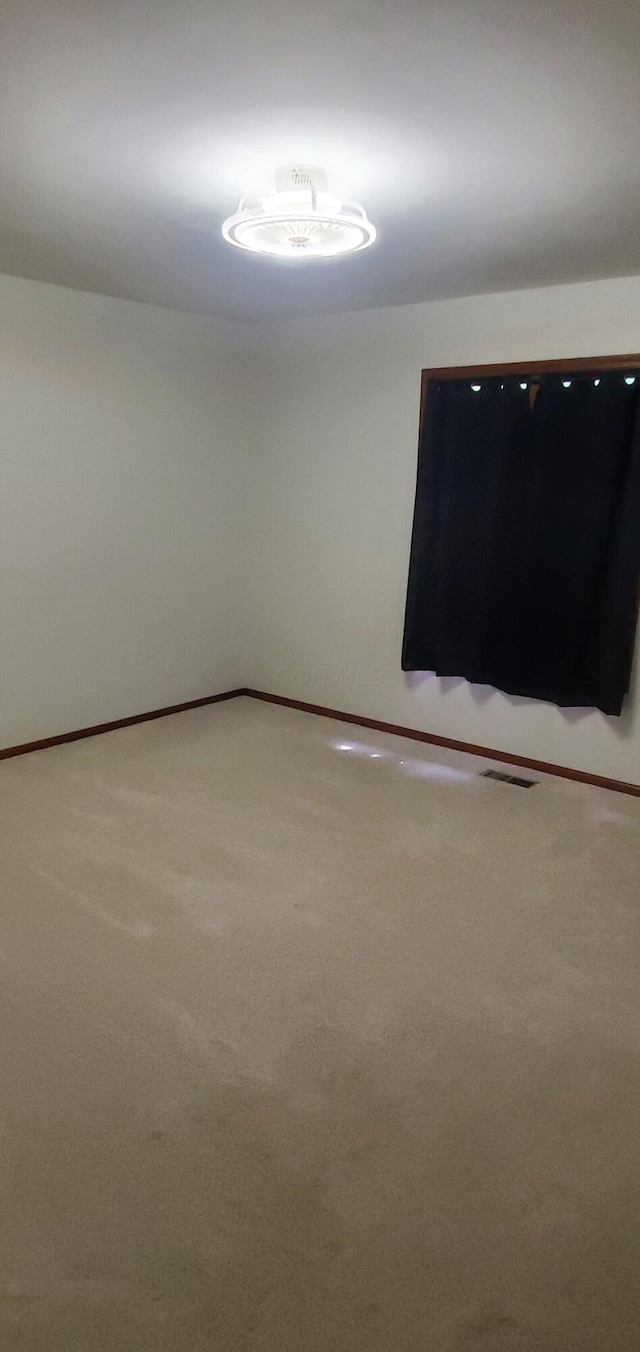 unfurnished room featuring baseboards, carpet flooring, and visible vents