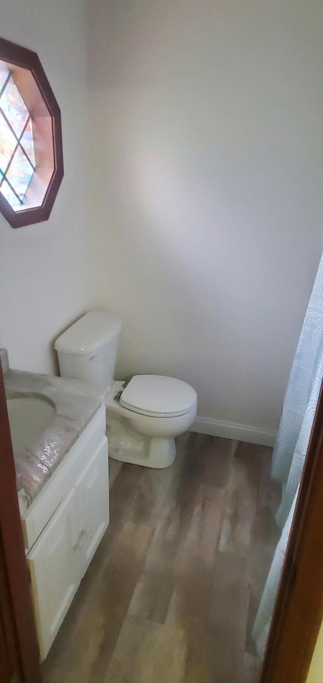 bathroom with vanity, baseboards, toilet, and wood finished floors