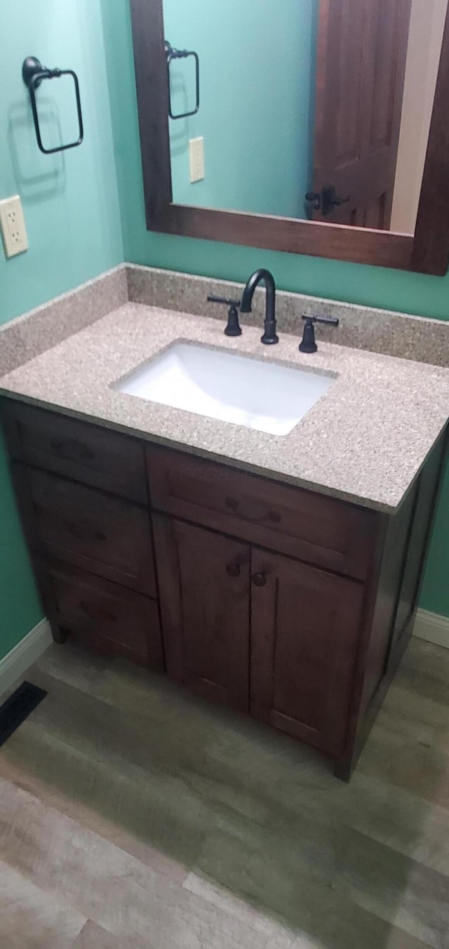 bathroom with baseboards, visible vents, wood finished floors, and vanity