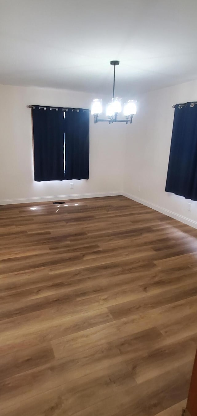 spare room featuring baseboards and wood finished floors