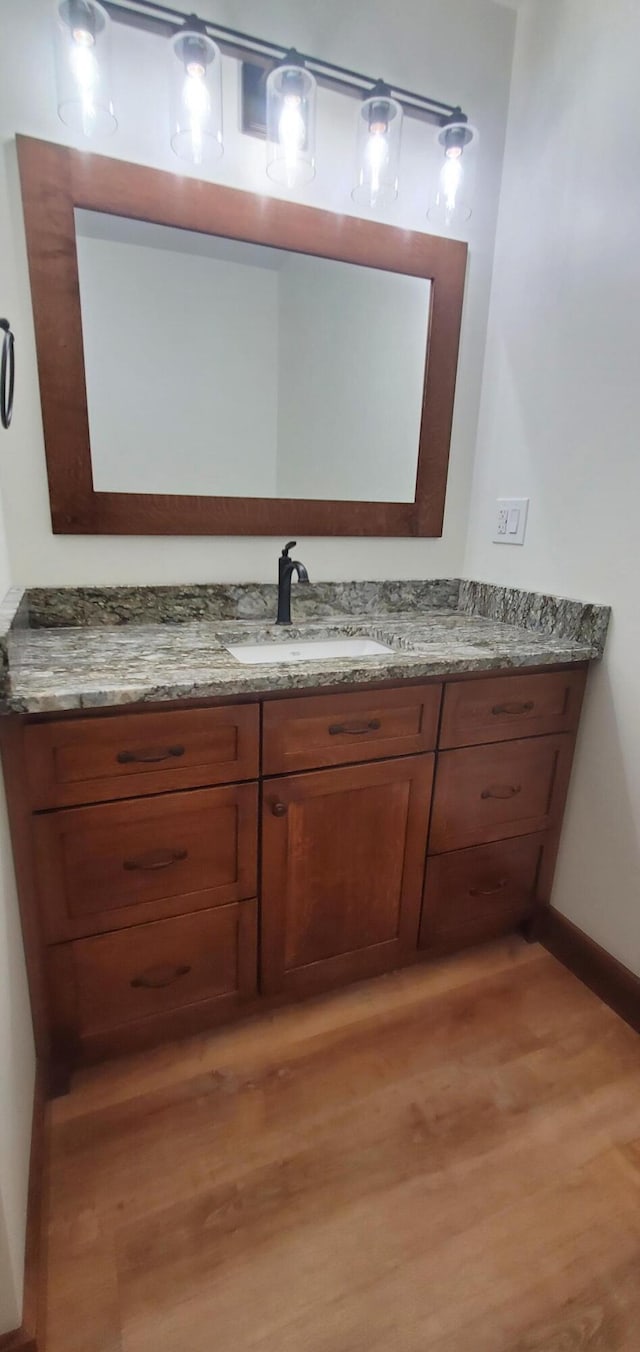 bathroom with baseboards, wood finished floors, and vanity