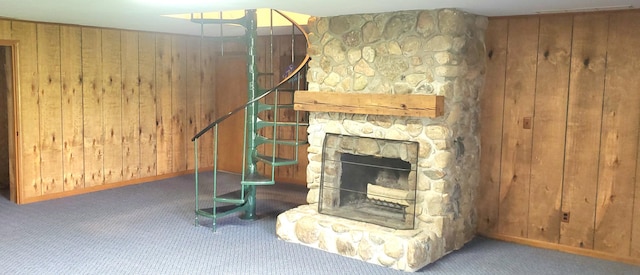 unfurnished living room with wooden walls, baseboards, carpet, and a fireplace