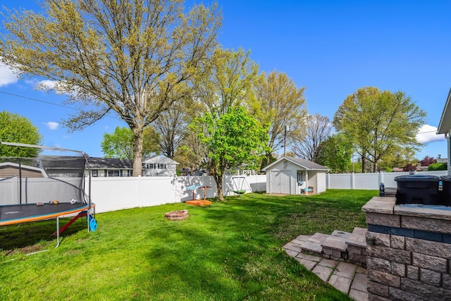 1083 Martha Ave, Bucyrus, OH 44820 - view of yard featuring a storage unit, a trampoline, a hot tub, a fenced backyard, and an outdoor structure