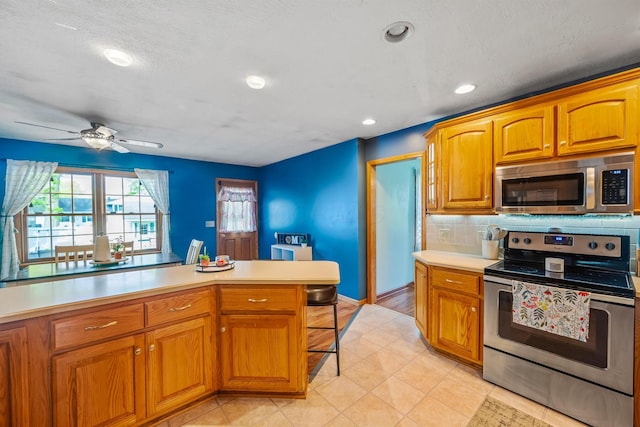 1083 Martha Ave, Bucyrus, OH 44820 - kitchen featuring light countertops, decorative backsplash, a ceiling fan, and stainless steel appliances