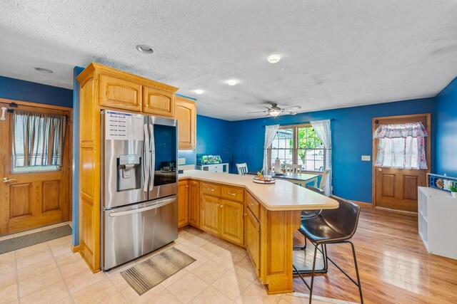 1083 Martha Ave, Bucyrus, OH 44820 - kitchen with a peninsula, ceiling fan, a kitchen bar, light countertops, and stainless steel fridge with ice dispenser