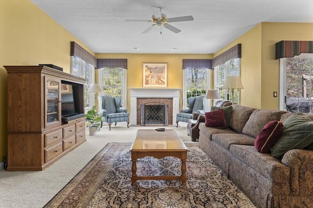 carpeted living area with a ceiling fan, a brick fireplace, and a wealth of natural light