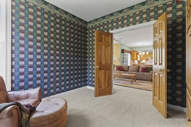 sitting room with carpet floors, baseboards, a chandelier, and wallpapered walls