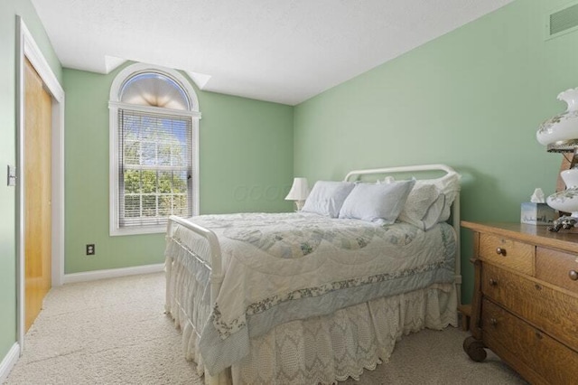 bedroom with visible vents, baseboards, and light carpet