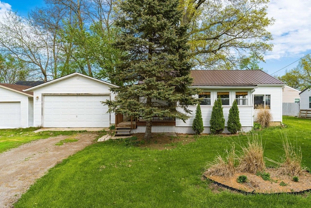 view of front of property featuring dirt driveway, a front lawn, a detached garage, and metal roof